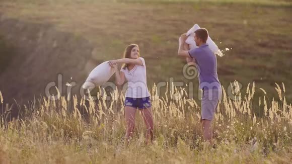 枕头大战年轻夫妇正疯狂地玩着一个女人和朋友一起打枕头视频的预览图