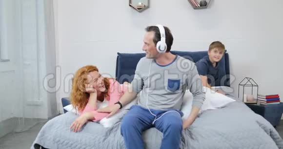 快乐家庭使用新耳机听音乐在卧室度过美好的早晨视频的预览图