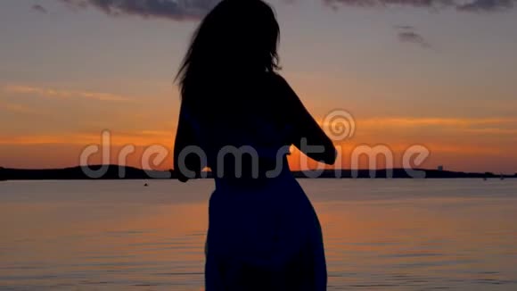 日落时分幸福的女人来到海滩举起双臂转身视频的预览图