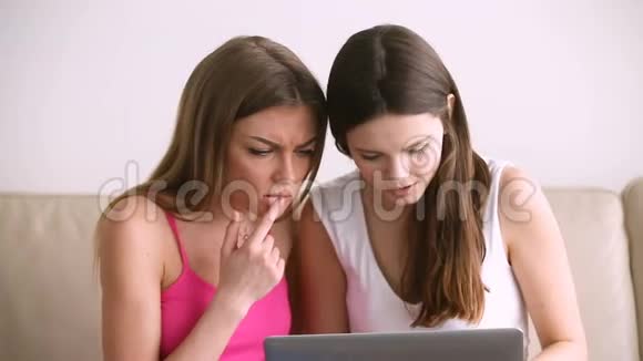 两个兴奋的漂亮女孩用笔记本电脑在网上购物视频的预览图