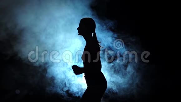 女士在黑色背景的烟雾聚光灯下奔跑剪影慢动作视频的预览图