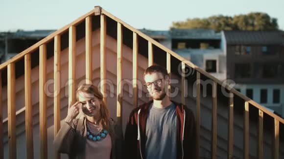 年轻漂亮的夫妇站在屋顶上欣赏日落时的风景浪漫的男女约会视频的预览图