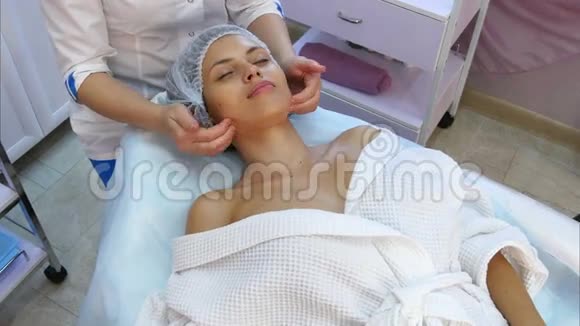 美丽的年轻女子接受面部按摩闭着眼睛在水疗沙龙视频的预览图
