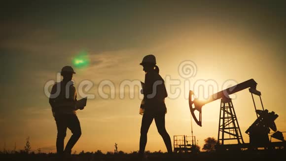 剪影两位工程师在日落时在背景上握手一台油泵工业石油和天然气的概念视频的预览图