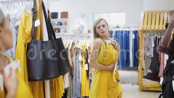 女人穿着精品店的黄色连衣裙时尚时尚的女孩留在镜子前年轻和视频的预览图