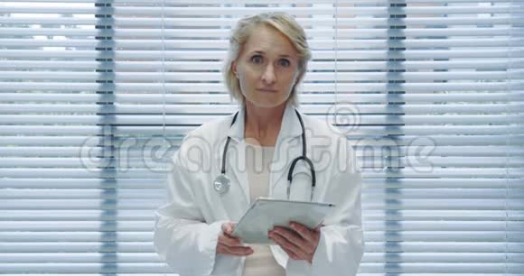 中年女性医生使用平板电脑并与摄像头交谈4k视频的预览图