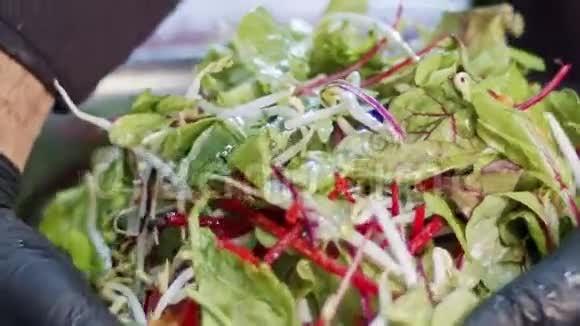 用胡萝卜树叶莴苣和芽菜慢动作制作的绿色沙拉视频的预览图