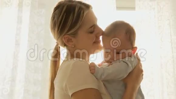 欢快的年轻母亲和她的小男孩在大窗户前晒太阳的画像视频的预览图