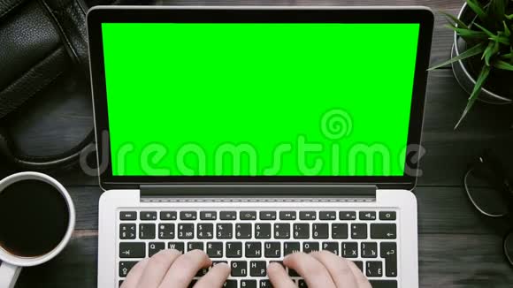 从上面可以看到男性双手在白色办公桌上用绿色屏幕工作视频的预览图