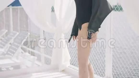 穿着黑色衣服的女孩和戴着太阳镜在白色露台的海边摆姿势4K视频的预览图