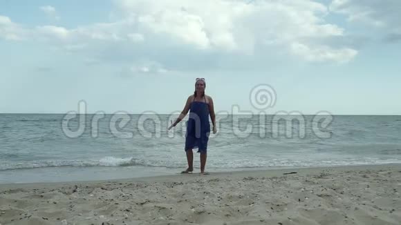 在海滩上穿蓝色裙子的女人视频的预览图