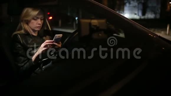 女孩晚上在车里用智能手机发短信视频的预览图