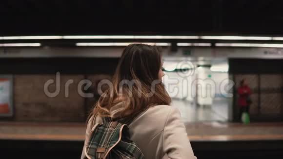 布鲁内特女士站在火车站等她的火车晚上在地下看快车的女孩视频的预览图