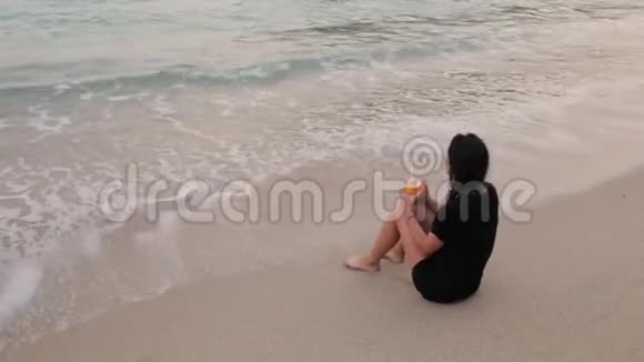 一个女孩在沙滩上喝鸡尾酒视频的预览图