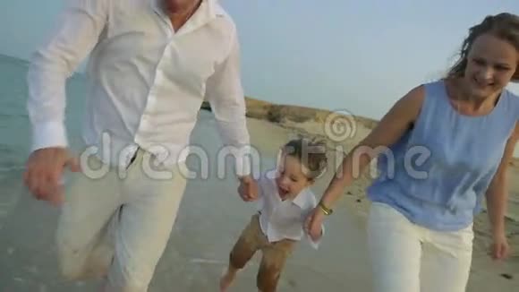 年轻的一家人在海滩上跑步视频的预览图