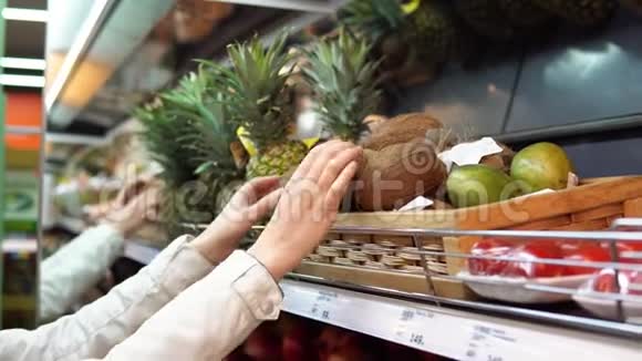 一位年轻妇女在超市挑选和购买椰子视频的预览图