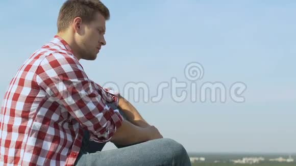 坐在大楼屋顶上的愤怒的男人看着城市全景视频的预览图