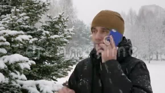 冬林一个年轻人在打电话大雪纷飞他钦佩雪和树的两边一个黑暗中的人视频的预览图