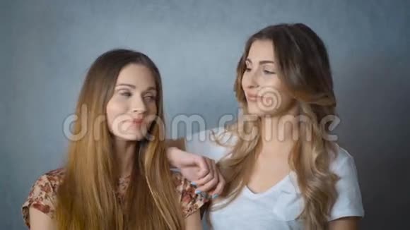 两个美丽的女孩微笑着看着工作室里的相机的肖像视频的预览图