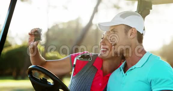 两个快乐的高尔夫球手在高尔夫车上自拍视频的预览图