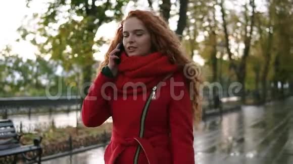 秋日散步时一位年轻的美女在黄红叶背景下用手机聊天视频的预览图