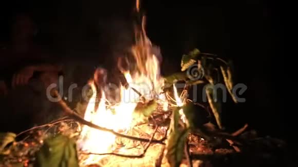 在篝火旁玩得开心的一群朋友面前燃烧着火视频的预览图