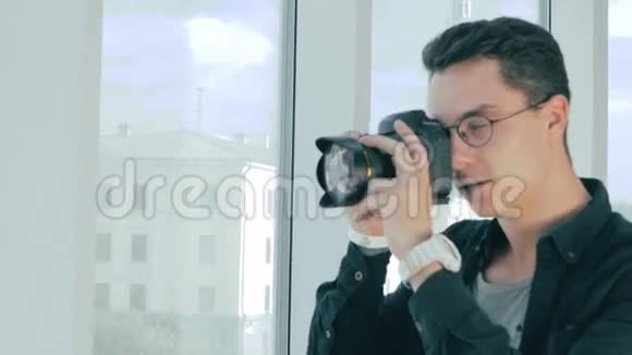 专业摄影师在现代办公室全景窗口附近用专业相机拍照视频的预览图