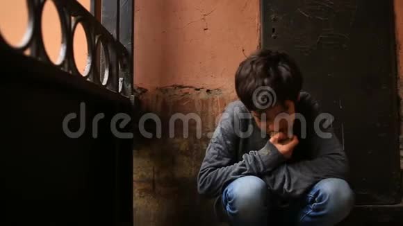 一个无家可归的少年在炉栅的背景下在门口吃面包皮视频的预览图