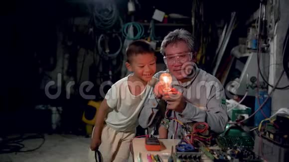 年长的祖父和孙子坐在房子前面的椅子上一起享受灯泡视频的预览图