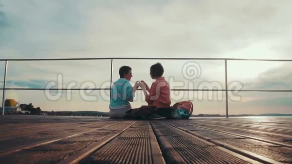 两个女朋友在坐在木墩边上的池塘边互相喂饭欢乐的夏日视频的预览图