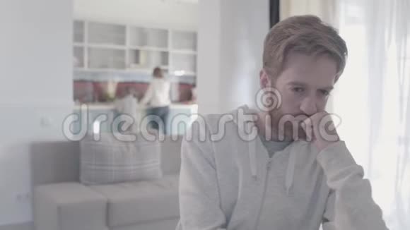 站在客厅里的一幅悲伤的胡子男的肖像女人和男孩在后台家庭关系视频的预览图