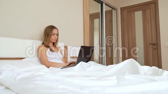 女人在床上用笔记本电脑打字视频的预览图