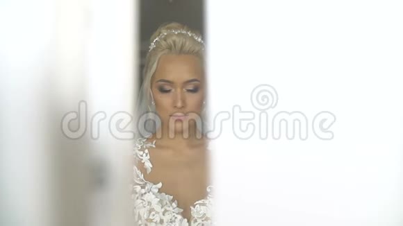 美丽美丽的新娘的肖像完美的化妆和时尚的服装摆在相机和纠正她视频的预览图