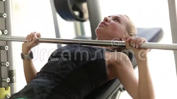 年轻迷人的女士在健身房锻炼举起杠铃胸部肌肉锻炼视频的预览图