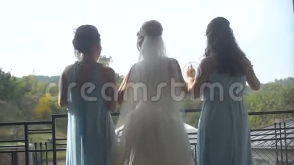 优雅的新娘穿着奢华的长裙两位伴娘穿着蓝色的裙子她的后景正在幸福地跳舞视频的预览图