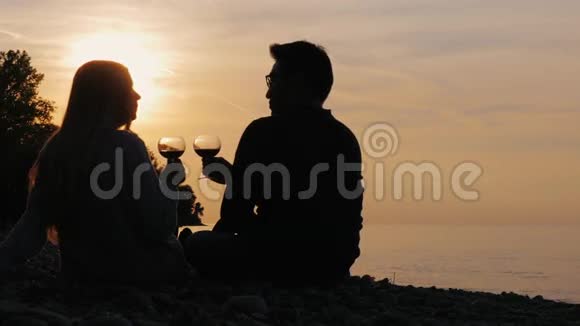 浪漫的多民族夫妇在海滩或湖边喝酒日落时人们可以看到他们的轮廓亚洲视频的预览图