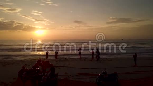 美丽的黄昏日落在沙滩上的海面上早上骑摩托车观看金色日出的人群视频的预览图