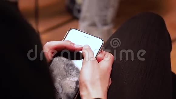 穿着黑色裤子的女孩坐着拿着她的手机屏幕上沾满了手指高清高清视频的预览图