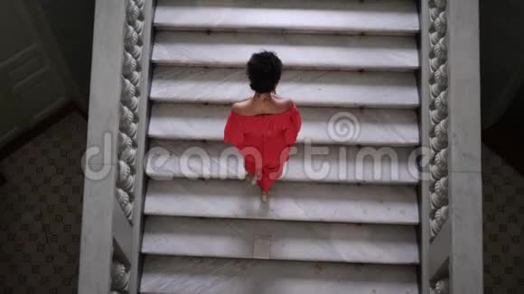 穿着高跟鞋的红衣女子无法辨认她爬上了一个大楼梯视频的预览图