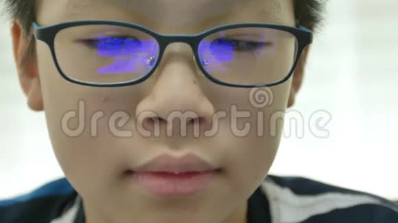 在智能手机上玩游戏的小亚裔男孩眼镜上有反射蓝盒视频的预览图