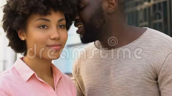非洲男友对女朋友耳语情话幸福的微笑情侣视频的预览图