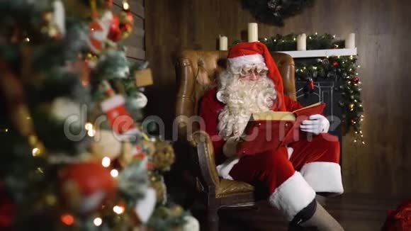 圣诞老人拿着玩具和灯在圣诞树附近的旧红绸专辑视频的预览图