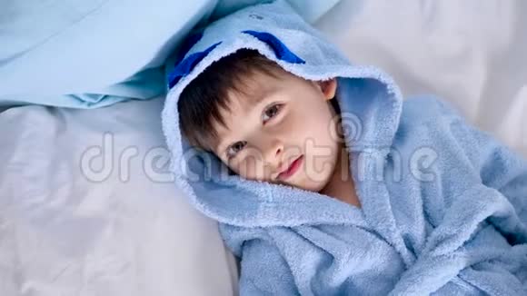 穿着蓝色长袍的孩子躺在床上视频的预览图