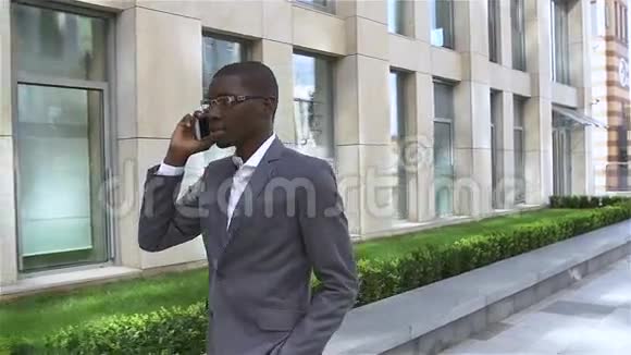 非裔美国商人用手机说话站在他的办公室前面慢动作视频的预览图