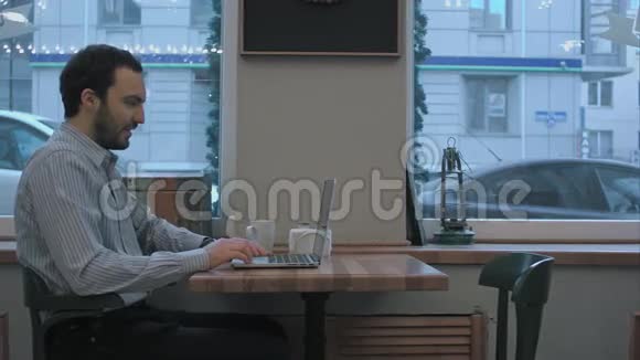 帅哥商人在咖啡馆里通过笔记本电脑视频聊天视频的预览图