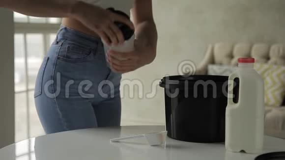 年轻女子站在厨房里把乳清倒入摇床视频的预览图
