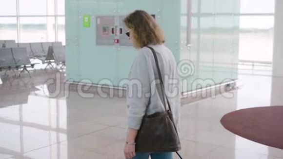 机场里的一个金发女郎带着滚动的行李箱包走路视频的预览图