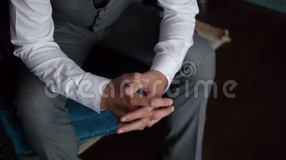 一个穿着时髦的男人坐在一张漂亮的椅子上双手合拢被锁起来视频的预览图