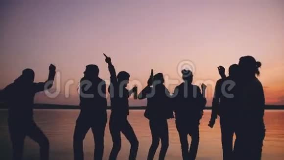 团体青年舞蹈家在日落时在海滩上举行派对视频的预览图