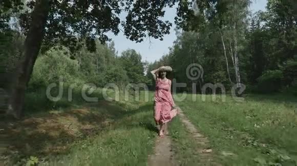 带帽子的年轻女子在草地上奔跑的后景慢动作视频的预览图